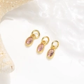 Makroaufnahme von drei ovalen rosa Zirkon-Anhängern mit Goldringen für DIY-Schmuck - Rosa
