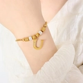 Elegante goudkleurige kralenarmband met een met strassteentjes bezette letter U-hanger - Gouden Armband - Letter U