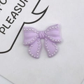 Close-up of purple resin bow DIY accessory with white faux pearl trim for phone cases - Purple
