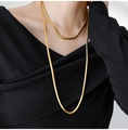 Dettaglio macro di catene a serpente dorate a strati su un top nero dallo stile vintage - Oro