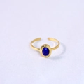 Detail of a gold adjustable ring with an oval dark blue natural stone on a white surface - Lapis Lazuli