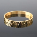 Detail of golden stainless steel bracelet with geometric triangular texture on black mirror - Engraved Triangle Bangle Gold