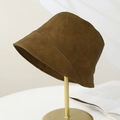 Detail view of a caramel faux suede bucket hat on a gold metal stand with warm lighting - Brown