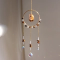 Detail of sun catcher featuring golden wire, brown stones, and multifaceted crystal prism - Tiger's Eye