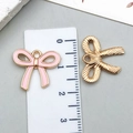 Pink enamel and gold bow charms shown next to a ruler for accurate size reference - Small KC Gold Pink Hollow Bowknot