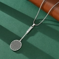 Detailed view of silver badminton racket pendant necklace on textured green background - Badminton Racket Pendant