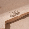 Macro detail of silver C-shaped geometric earrings with sparkling pavé zircon stones - Silver