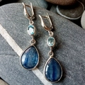 Vintage silver drop earrings with blue gemstones displayed on natural pebbles - Kyanite Waterdrop Style / Silver