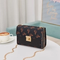Mini black crossbody bag with unicorn prints and gold chain strap in a lifestyle setting - Black