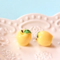Pair of yellow resin apple charms with green leaves on a decorative beige tray - Small / Yellow