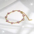 Detailopname van de gouden hartjesarmband met paarse boze oog bedeltjes op wit zijde - Paars Oog