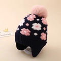 Close-up of navy knit winter hat for girls with flower patterns and a pink faux fur pompom - One Size (3-8Y) / Navy Blue