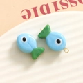Macro shot of 3D blue and green glass fish charms with gold rings on white ceramic plate - 3D Color Matching Fish / Sky Blue and Green