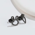 Macro shot of asymmetric black rabbit and carrot stud earrings in polished stainless steel - Black