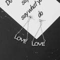Silver LOVE letter tassel earrings with sparkling rhinestones on black marble background - Silver LOVE Letter Tassel