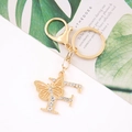 Close-up of golden letter F keychain with sparkling crystal butterfly on an art card - Letter F