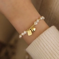 Elegant freshwater pearl bracelet with gold heart and 'Good Luck' charms on wrist - Good Luck Tag Faux Pearl Bracelet