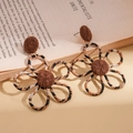 Macro shot of fabric leopard print flower earrings with textured woven brown centers - Black