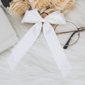 Close-up of elegant white satin ribbon bow hair clip on a soft white plush surface - White