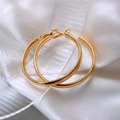 Macro detail of classic golden hoop earrings resting on elegant white silk fabric - Plain Large Gold Hoop Post