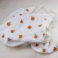 Detailed view of white cotton baby blanket with orange fruit print and fringe trim - 100x120cm / Fruit/Orange