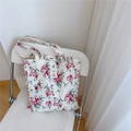 Dettaglio borsa tote in tela floreale con tulipani rossi su una sedia minimalista - Bianco con fiori rossi