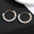 Macro shot of gold wire-wrapped earrings featuring white marbled natural stone beads - White Texture