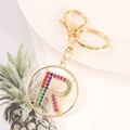 Close-up of gold letter R keychain featuring colorful rhinestones on a white plate - Letter R