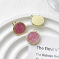 Detail of pink enamel round pendant charms on a white display stand for DIY jewelry making - Pink