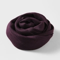 Solid deep purple cotton linen scarf folded into a rose shape on light grey background - Violet