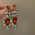 Macro view of geometric drop tassel earrings with sparkling crystals and gold base - Multicolor Water Drop