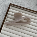 Close-up of beige wave resin hair claw clip displayed on linen tray in soft light - Premium Skintone
