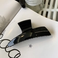 Detail of glossy black large hair claw clip on a magazine with high-shine finish - Glossy Black