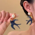 Gros plan détaillé de la boucle d'oreille hirondelle avec perle blanche et fini bleu - 39# Style Hirondelle Vintage Avec Fleur