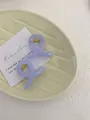 Close-up of lavender purple mini hair claws with gold metal springs on a ceramic plate - Mini Butterfly Clip X-Shaped (Approx. 4cm) / Transparent Sky Blue