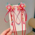 Detailed close-up of pink flower hair clips with red silk ribbons and dangling pearls - Single Flower Blooming Pair