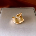 Detailed view of wide irregular gold wave ring on a brushed grey jewelry display stand - Adjustable Open (WR380) / Gold