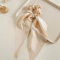Close-up of champagne satin scrunchie with long ribbons on a minimalist tray - Beige