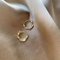 Elegante gouden gedraaide oorringen gepresenteerd op luxe champagnekleurige satijnen stof - S100 Gedraaide Textuur Oorbellen / Goud