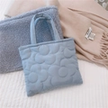 Dettaglio della borsa imbottita celeste con motivo floreale trapuntato su letto bianco - Celeste