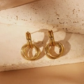 Close-up of golden interlocking multi-ring earrings on marble and champagne silk - Multi-Ring Intertwined Style