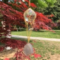 Macro shot of K9 crystal ball with agate slice hanging on a golden chain in a park - White