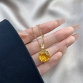 Détail d'un collier en or avec pendentif rond en zircon jaune sur un fond en soie élégant - 0406-Or Rond Pierre Jaune