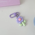 Detail of a cute purple resin flower keychain with pink core and green leaf on white desk - Purple