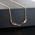 Gros plan macro d'un délicat collier pendentif bois de renne doré sur fond sombre - Collier Bois de Cerf (2315) / Or Rose (Collier)