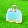 Mini handbag-shaped opal stone pendant with golden metal handle on green grass background - Opal (Synthetic)