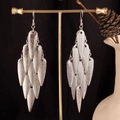 Detailed close-up of tiered silver leaf-shaped tassel earrings on a gold display stand - Inverted Waterdrop / Silver