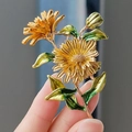 Elegante spilla a margherita dorata con foglie smaltate verdi e trama metallica vintage - Tre Margherite Giallo