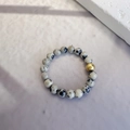 Minimalist Dalmatian Jasper beaded ring with a gold accent bead on a textured surface - Elastic Free Size / Dalmatian Stone Color