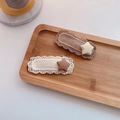 Detail view of two knitted lace hair clips with matte star accents on a wooden tray - Star Style